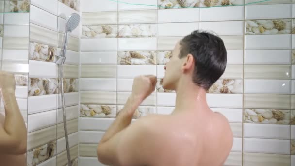 młody człowiek bierze prysznic. facet myje i śpiewa pod prysznicem - Materiał filmowy, wideo
