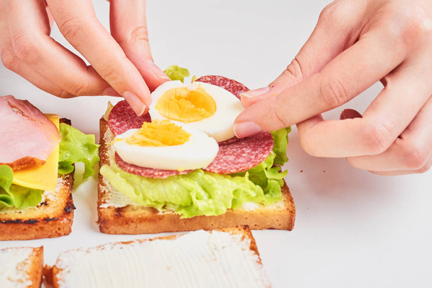 Vrouw handen Maak je sandwich op een witte achtergrond, close-up - Foto, afbeelding