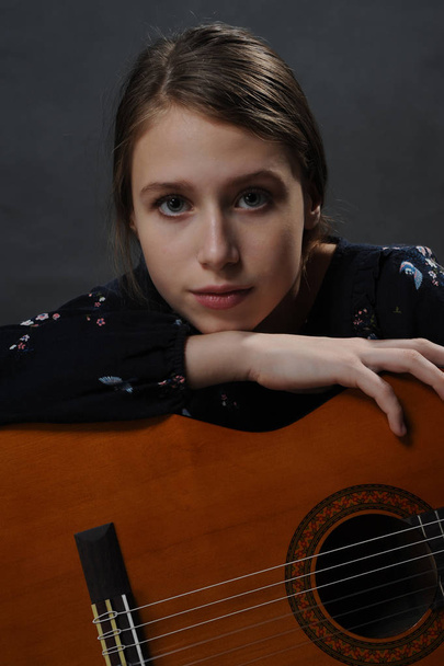 Girl with guitar. Portrait. Studio light. Dark background. - Foto, Imagem