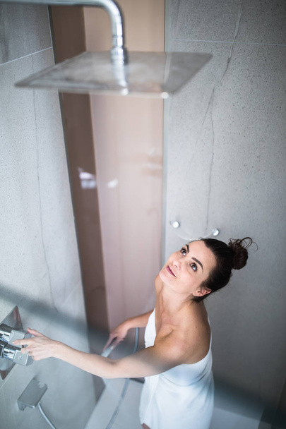 Woman taking a long hot shower washing her hair in a modern design bathroom - Photo, Image