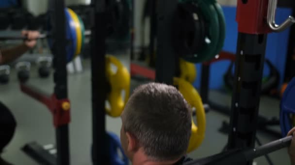 View from the back. Man crouches with a barbell 4K Slow Mo - Footage, Video
