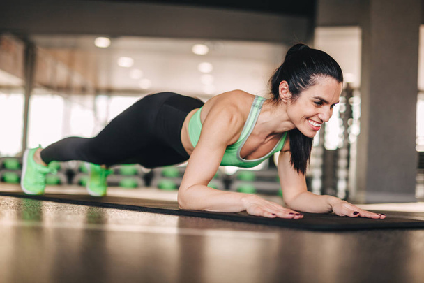 Smiling lady doing plank in gym - Foto, Imagen