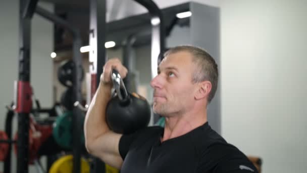 Close-up. Handsome guy doing exercise with a kettlebell in the gym 4K Slow Mo - Footage, Video