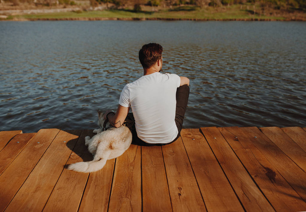 Man with dog on remote wooden pier - Фото, изображение