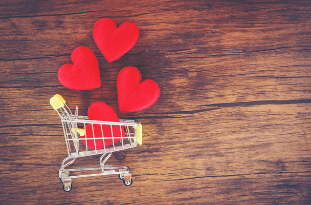 Valentines dag winkelen en rood hart op shopping cart liefde concept / vakantie voor Valentijnsdag liefde winkelen op houten achtergrond Toon vintage stijl bovenaanzicht kopiëren ruimte - Shopping vakantie - Foto, afbeelding