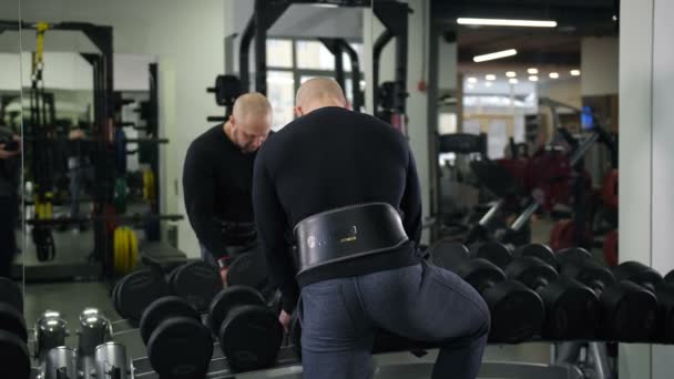 Bodybuilder nimmt schwere Hanteln, schaut sich selbst im Spiegel an, macht die Übung 4k slow mo - Filmmaterial, Video