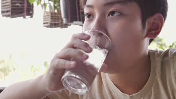 Slow motion of asian boy drinks water from a glass after breakfast, Close up teen boy with glass of water. - Кадри, відео