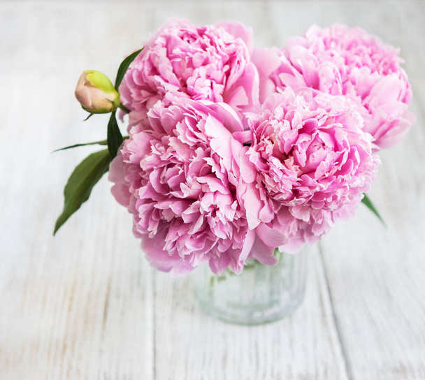 白い木製のテーブルの上にピンクの牡丹花と花瓶 - 写真・画像