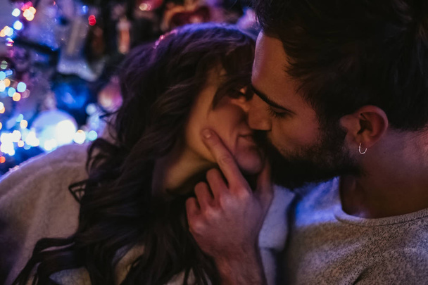 Pari rakastunut suudella edessä joulukuusi
 - Valokuva, kuva