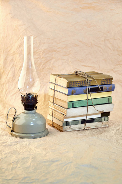 Petroleumlampe und Stapel alter Bücher an Schnur gebunden. - Foto, Bild