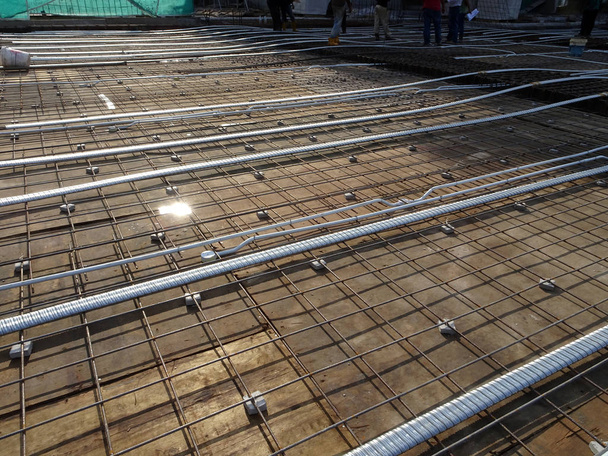 Pre-stress cable laid in round ducting and install in between the slab steel reinforcement bar at the construction site.    - Photo, Image