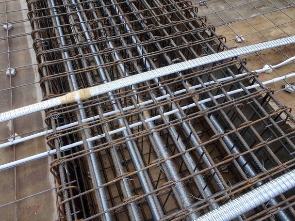 Cable de pre-tensión colocado en el conducto redondo e instalar entre la barra de refuerzo de acero de losa en el sitio de construcción
.    - Foto, imagen