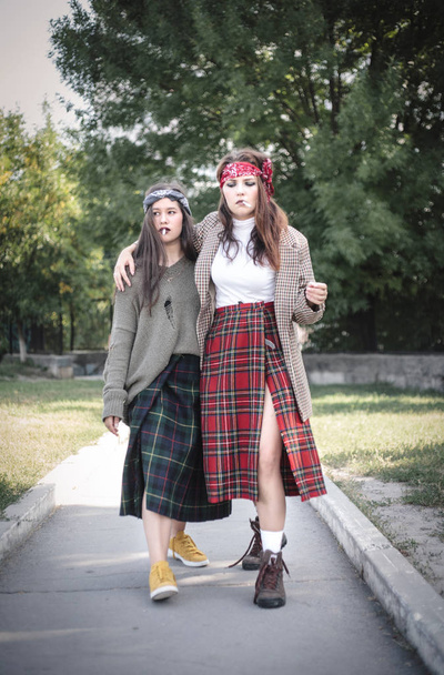 Dos chicas vestidas informalmente caminando por la calle con cigarrillos. Problemas con los adolescentes
. - Foto, imagen