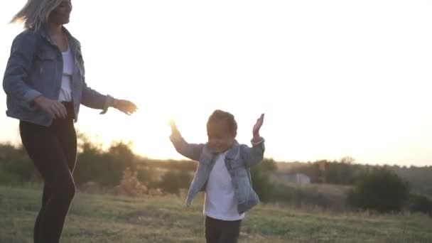 Cute little chinese girl jumping excited and claping her hands. Mixed race family, european mother and asian daughter spending time in the park on sunset. Warm spring or summer season - Footage, Video