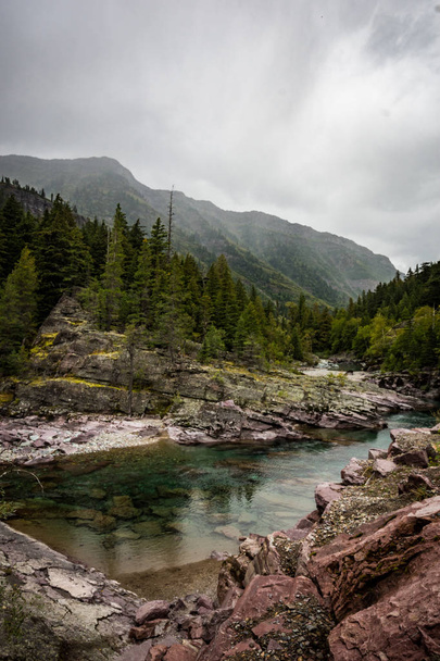 Clear teal waters of Haystack Creek along Going to the Sun Road in Glacier National Park. Overcast cloudy day - Foto, Imagem