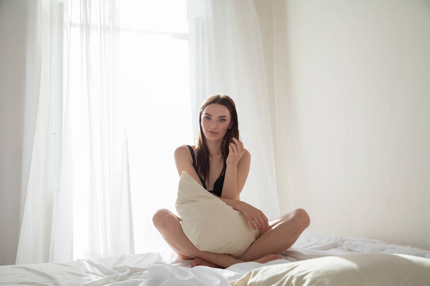 όμορφη γυναίκα με εσώρουχα ξαπλώνει στο κρεβάτι στην κρεβατοκάμαρα - Φωτογραφία, εικόνα