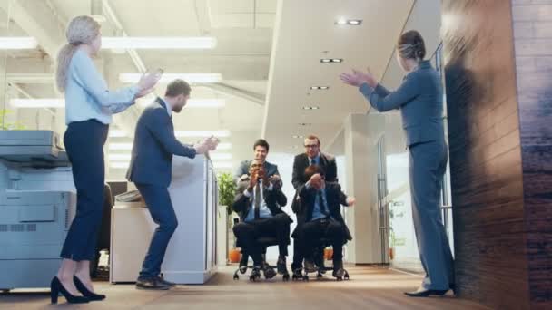 Bürostuhlrennen lustige multiethnische Geschäftsleute sitzen auf Stühlen im Flur des Firmengebäudes. Kollegen jubeln, applaudieren und jubeln. Feierlichkeiten zum Abschluss des Deals. - Filmmaterial, Video