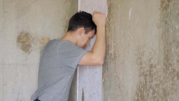 przygnębiony człowiek stojący i bije ściany - Materiał filmowy, wideo