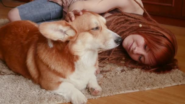 Young pretty woman with red dreadlocks having good time with corgi dog - Video