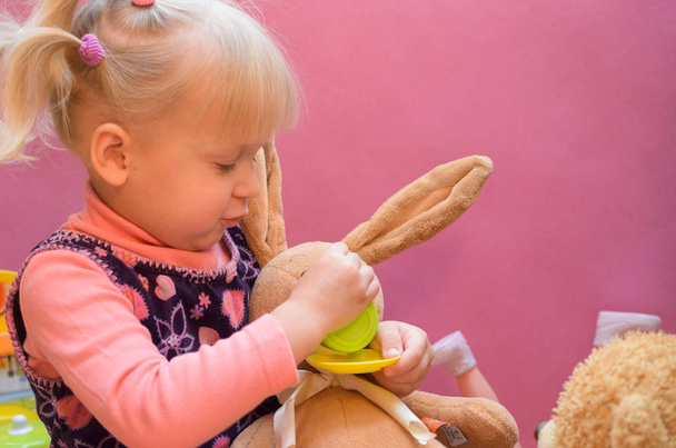 Het kleine meisje speelt met een zacht speelgoed. - Foto, afbeelding