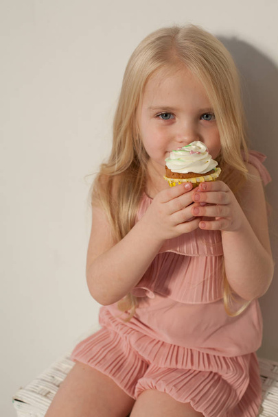 Маленькая девочка держит в руке сладкий кексовый торт
 - Фото, изображение