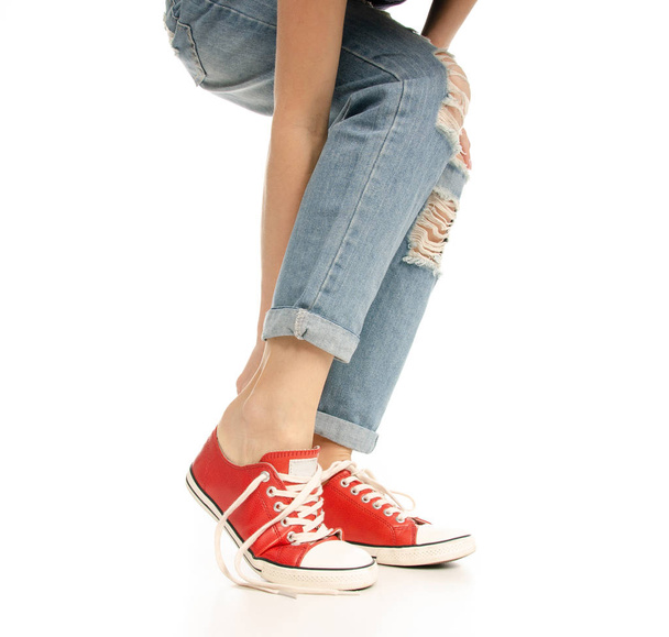 Woman legs feet jeans wearing red sneakers hipster style - Фото, изображение