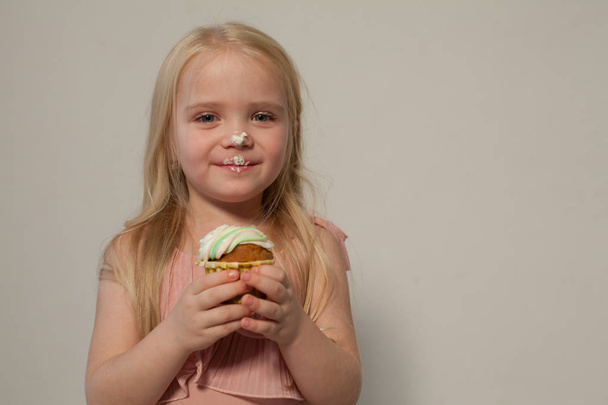 pieni tyttö kädessä pitää makea cupcake
 - Valokuva, kuva