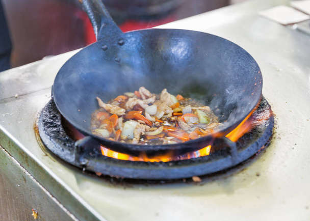 cocina al aire libre comida asiática en un wok en la estufa de gas primer plano
 - Foto, Imagen