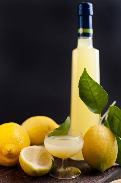 Limoncello in a bottle and a small shot with liquor. The traditional alcoholic beverage of Italy, from citrus. Fresh fruits and drinks. Free space for text - Zdjęcie, obraz