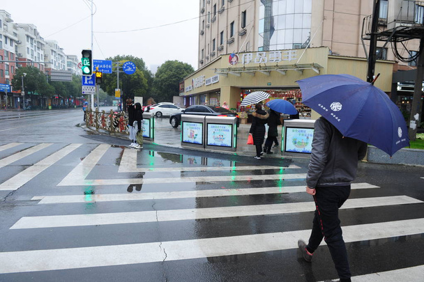 Pedestrians walk across a crosswalk when the automatic doors open as the traffic light turns green at the intersection of Huancheng Dong Lu and Baziqiao Lu of Fengxian District in Shanghai, China, 22 December 2018 - Fotoğraf, Görsel