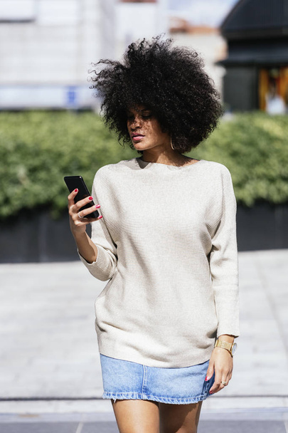 Portrait of attractive afro woman using mobile phone in the street. Business woman concept - Fotó, kép