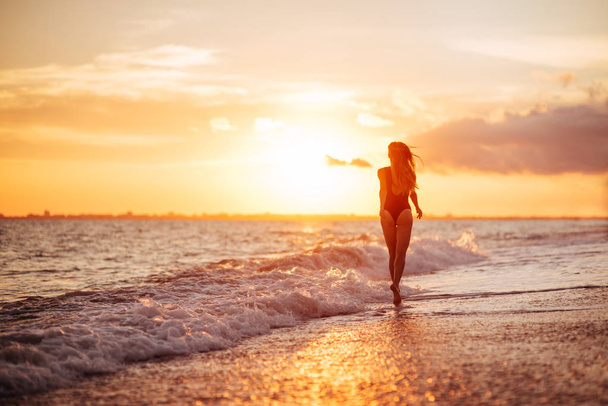 Unbekümmerte Frau tanzt im Sonnenuntergang am Strand. Urlaub Vitalität gesundes Wohnkonzept - Foto, Bild