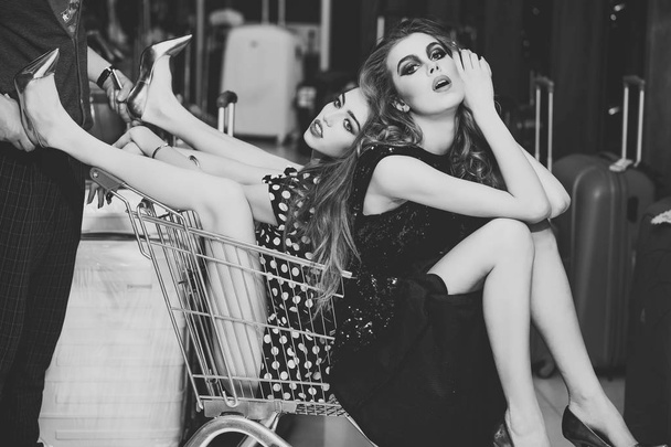 Women shoppers sit in shopping cart, trolley - Fotoğraf, Görsel