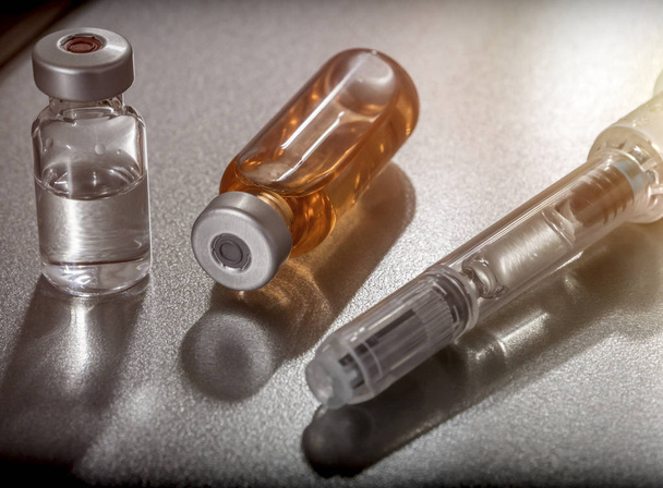 Enkele injectieflacons naast een spuit - Foto, afbeelding