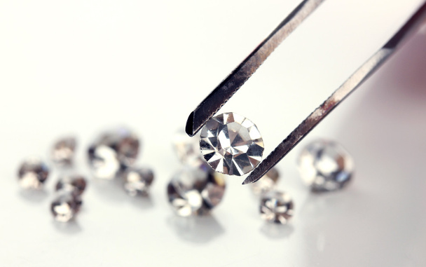 Beautiful shining crystal (diamond) in the tweezers, isolated on white - Fotografie, Obrázek