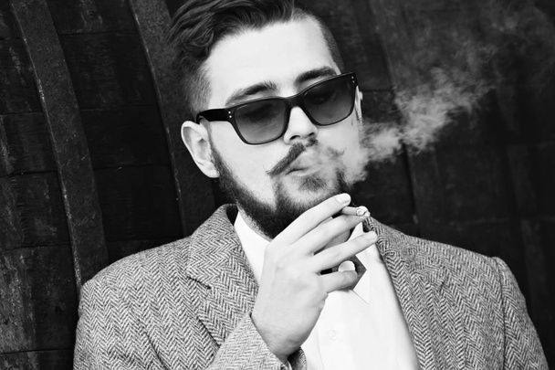 A closeup of a stylish young guy smoking and blowing the smoke out form his nose and mouth.The human emotions, facial expression concept. - Photo, Image