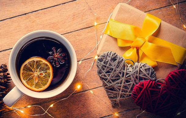 Cup of tea and Christmas box gift with pine cones and Fairy Lights on wooden background - Φωτογραφία, εικόνα