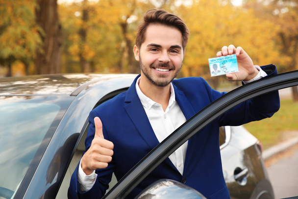 Junger Mann mit Führerschein in der Nähe von offenem Auto - Foto, Bild