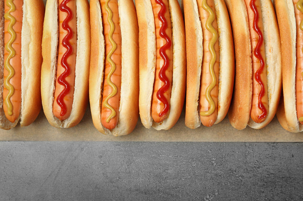 Tasty fresh hot dogs on grey background, top view - Fotoğraf, Görsel