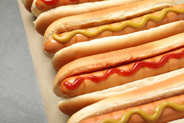 Tasty fresh hot dogs on grey table, closeup - Foto, afbeelding