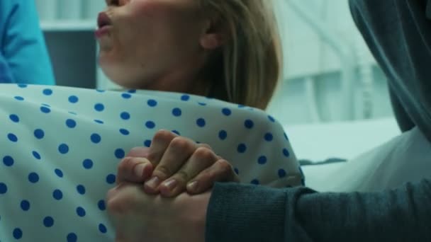 Close-up on a Face of a Woman in Labor Pushing Hard to Give Birth, Obstetricians Assisting, Spouse Holds Her Hand. Modern Maternity Hospital with Professional Midwives. - Materiał filmowy, wideo