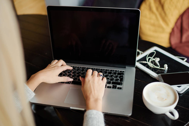 Lány kezét a digitális laptop és csésze kávé, egy fából készült asztal - Fotó, kép