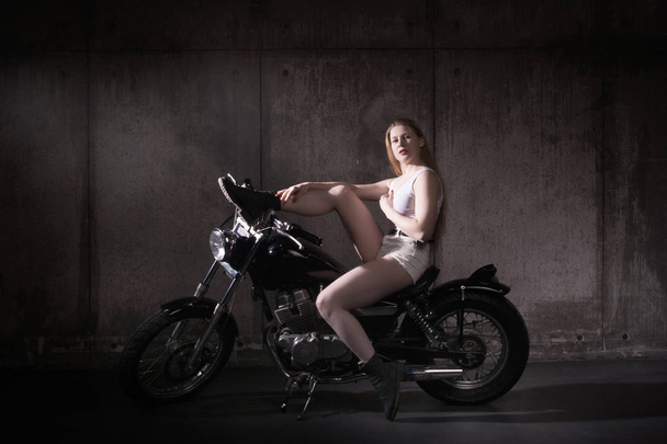 Güzel motorcu kız boş bir otoparktan bir motosiklet üzerinde - Fotoğraf, Görsel