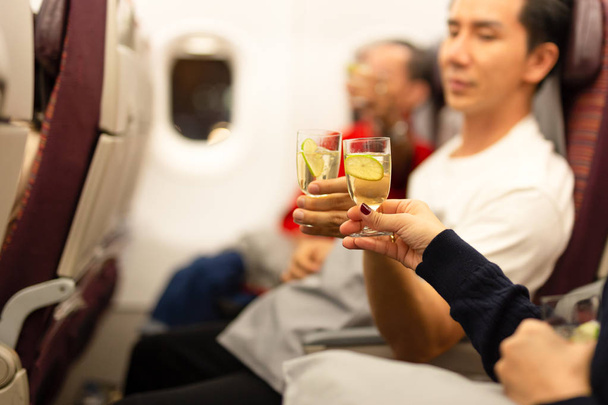 Onnelliset matkustajat paahtavat lasialkoholia lentokoneessa juhla lomalla
 - Valokuva, kuva