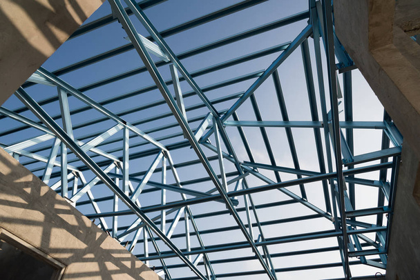 Estructura del marco de techo de acero para la construcción de edificios aislados sobre fondo azul del cielo
. - Foto, imagen