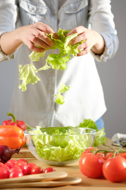 The girl prepares a salad of fresh vegetables. Vertical photo - Foto, Imagem