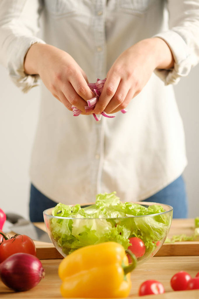 The girl prepares a vegetable salad. Vertical photo - Foto, afbeelding