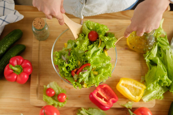 Girl interferes with vegetable salad. Cooking salad - Fotografie, Obrázek