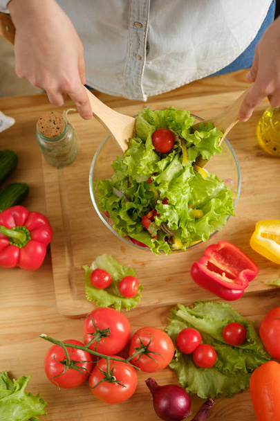 Girl interferes with vegetable salad. Cooking salad - Foto, afbeelding