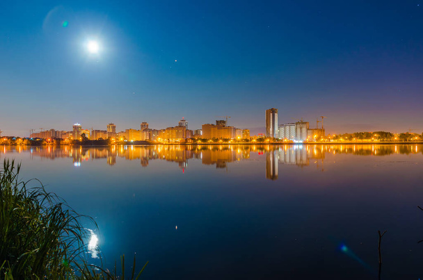 Éjszakai város fényeit a víz felszínén tükre - Fotó, kép